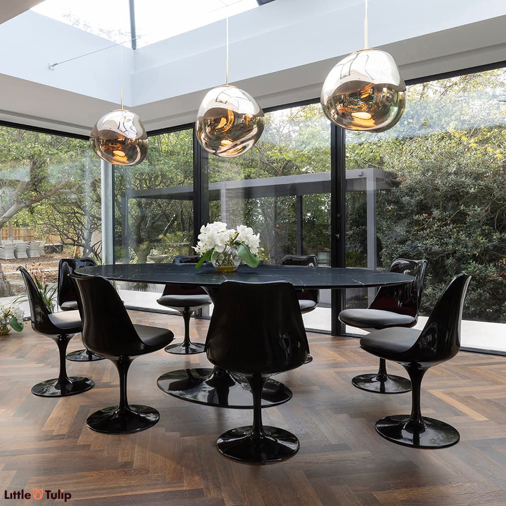 A stunning all black 244 Tulip Table with 8 side chairs and grey cushions displayed here in a well-lit natural floor space