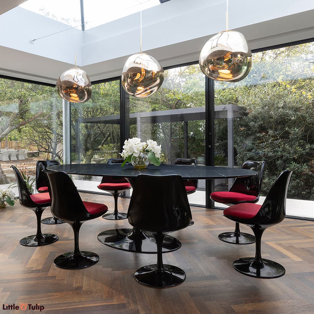 A stunning all black 244 Tulip Table with 8 side chairs and red cushions displayed here in a well-lit natural floor space