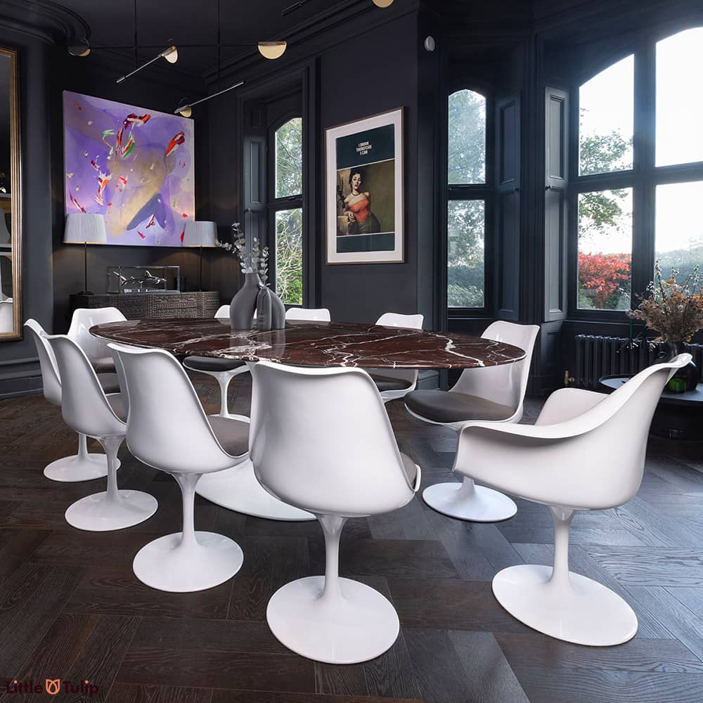 An artistic shot of the 200 levanto rosso Saarinen oval Dining table with 8 Tulip side chairs & 2 arms with grey cushions
