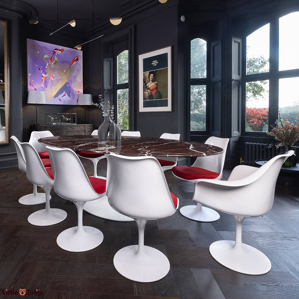An artistic shot of the 200 levanto rosso Saarinen oval Dining table with 8 Tulip side chairs & 2 arms with red cushions