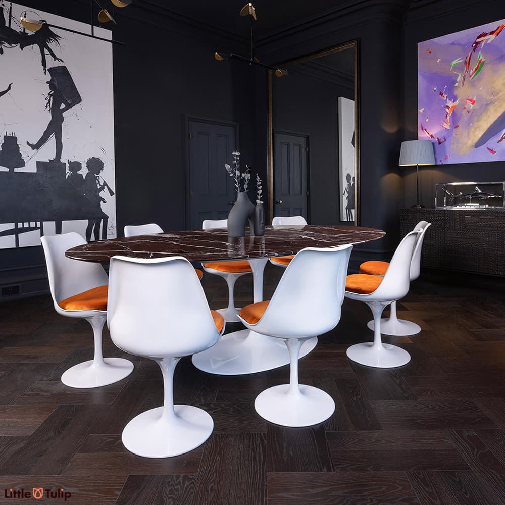 8 Tulip side chairs & orange cushions surround the 244 levanto rosso Saarinen oval dining table in this modern darkened room