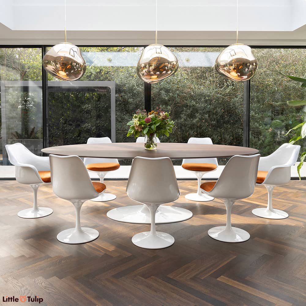 Walnut floor and walnut 244 Tulip table top contrast with white chairs and orange cushions, creating two distinct levels
