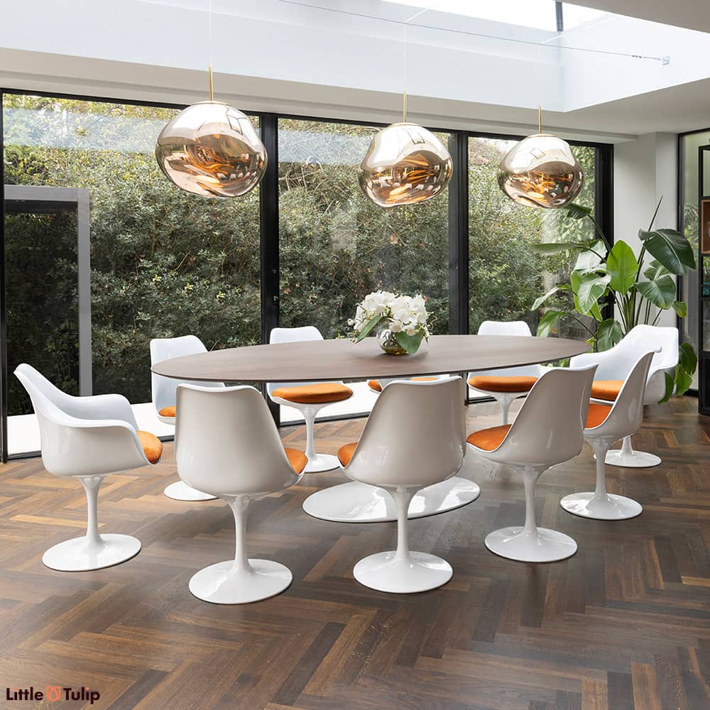 The walnut look elevates the 244 tulip table with 8 side and 2 arm chairs, featuring orange cushions for timeless charm