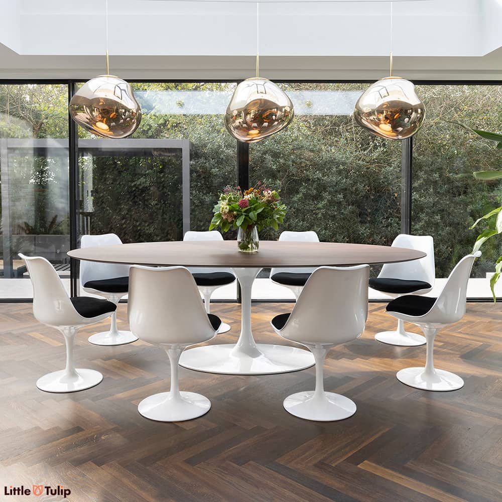 In this dining space, a walnut 244 Tulip table with 8 chairs and black cushions seamlessly continues the natural theme.
