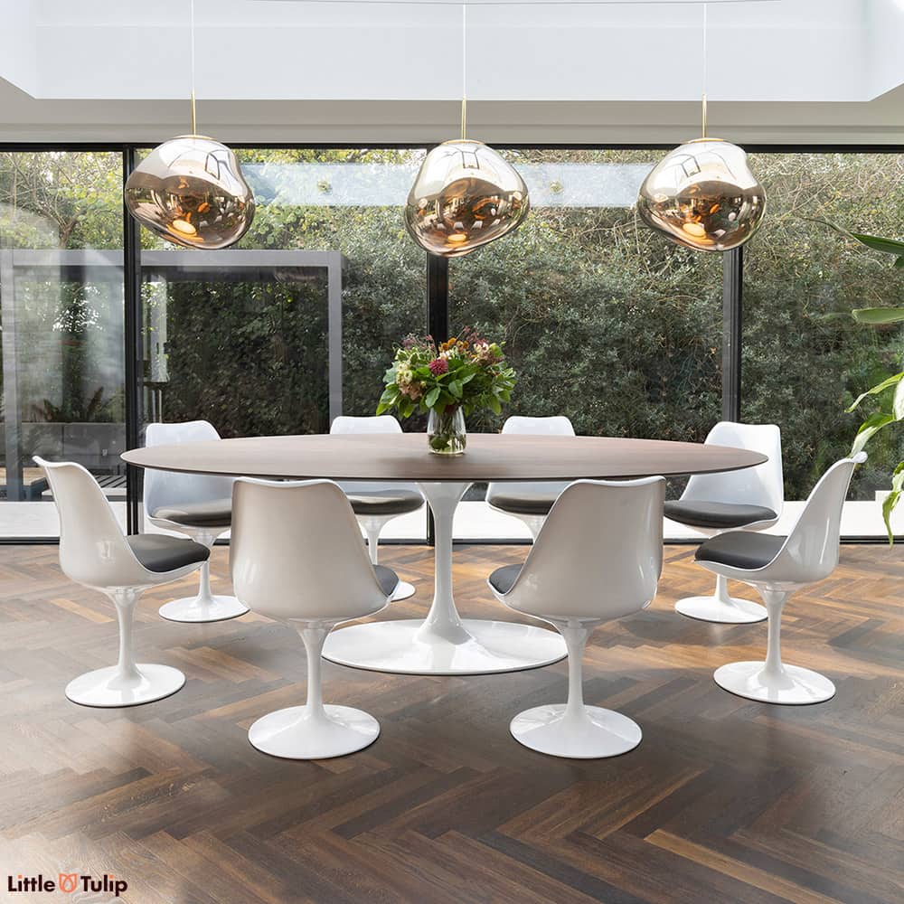 In this dining space, a walnut 244 Tulip table with 8 chairs and grey cushions seamlessly continues the natural theme.
