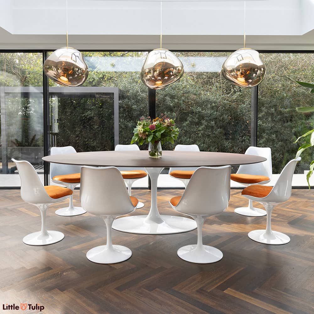 In this dining space, a walnut 244 Tulip table with 8 chairs and orange cushions seamlessly continues the natural theme.