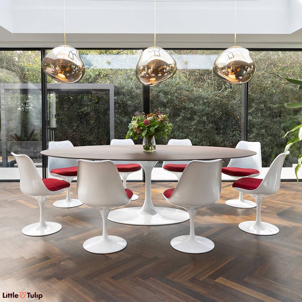 In this dining space, a walnut 244 Tulip table with 8 chairs and red cushions seamlessly continues the natural theme.