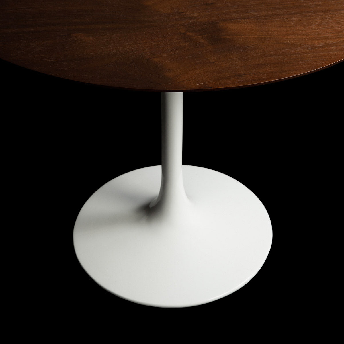 A top down angled view of the circular 90cm Tulip Table with a Natural Walnut Veneer top with beautiful grains evident throughout, on a black backdrop