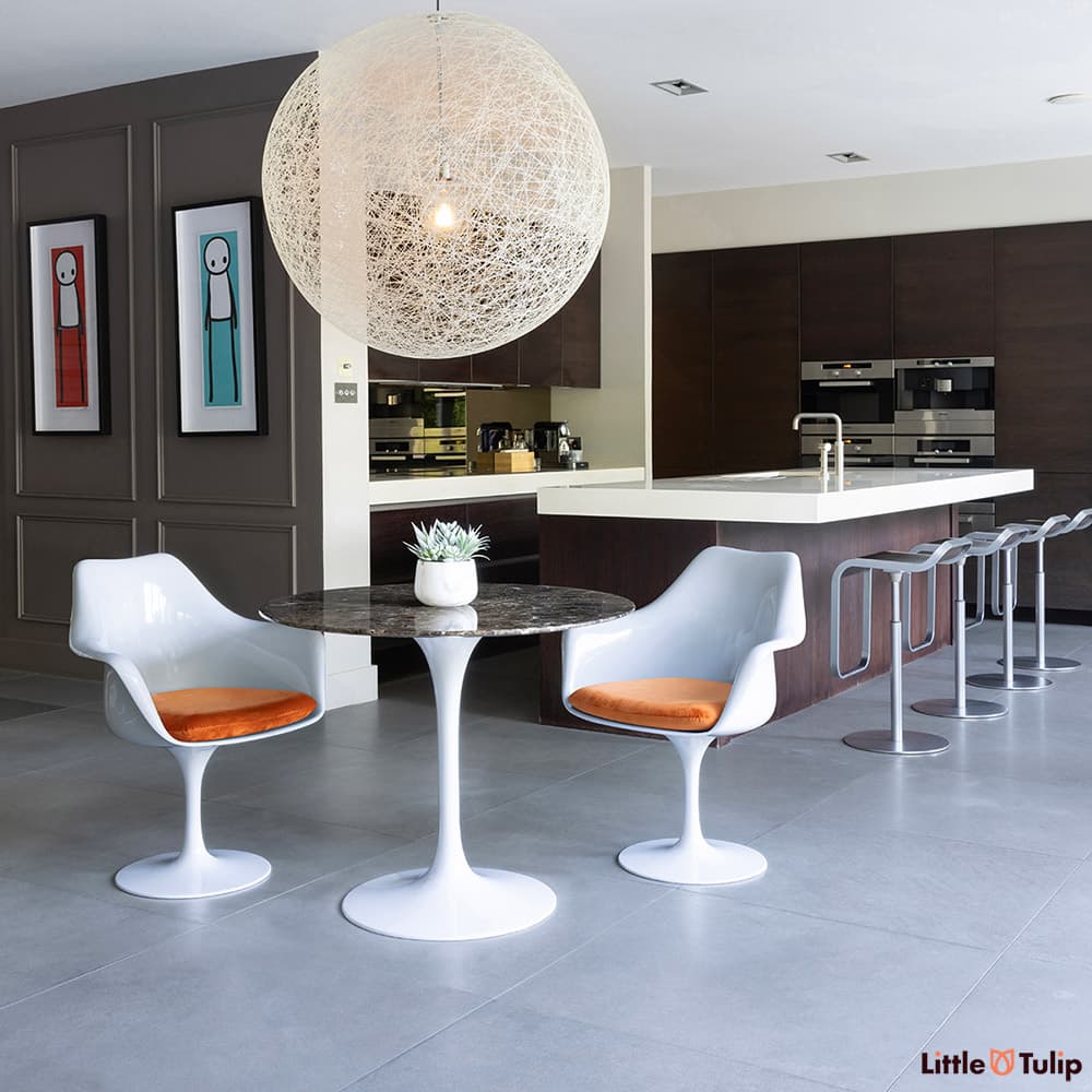 2 arm chairs with orange cushions and the 90cm emperador tulip table add the finishing touch to this modern dark wood kitchen