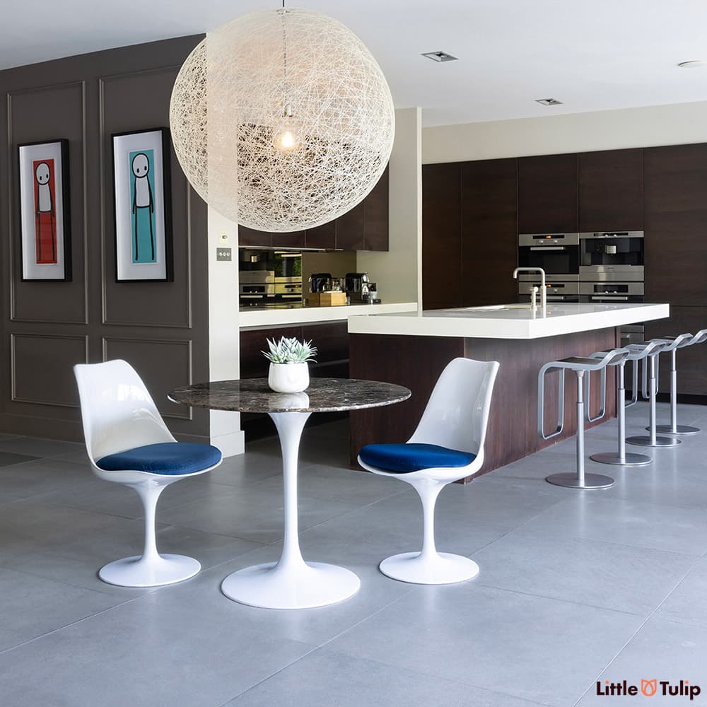 The perfect combination, 2 side chairs with blue cushions around the 90cm emperador tulip table in this fresh kitchen