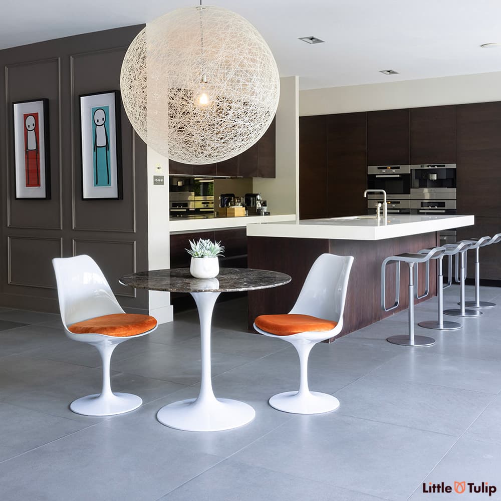The perfect combination, 2 side chairs with orange cushions around the 90cm emperador tulip table in this fresh kitchen