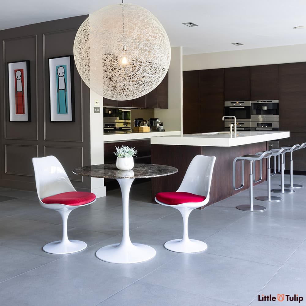 The perfect combination, 2 side chairs with red cushions around the 90cm emperador tulip table in this fresh kitchen