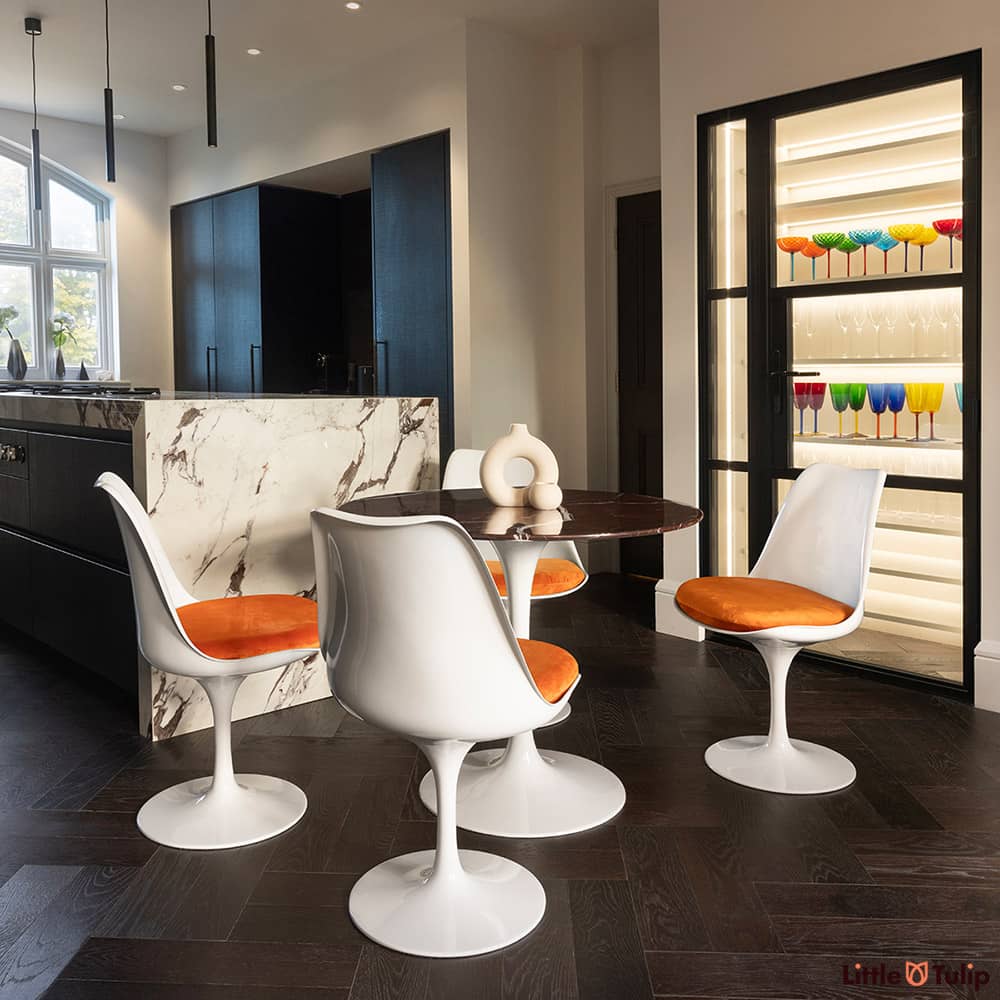 In a modern kitchen, centre stage, is the 90cm levanto rosso Saarinen dining table and 4 Tulip side chairs & orange cushions
