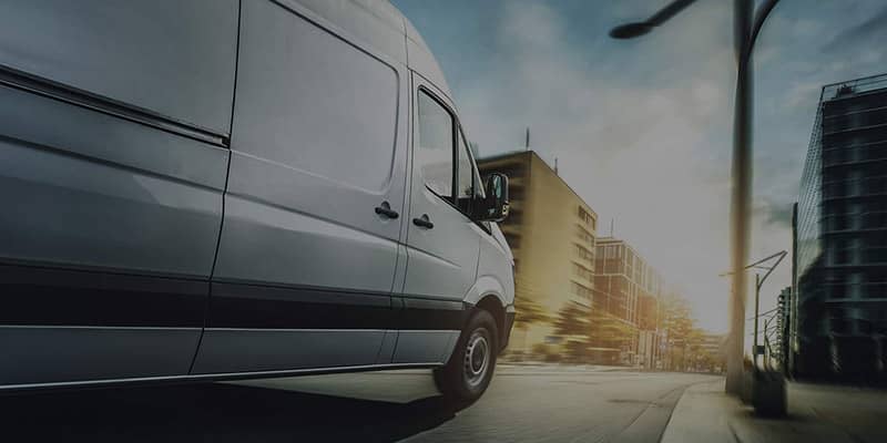 An image of a transit van making its way towards the end of the street is imagery used to show that your delivery is in good hands and on the way