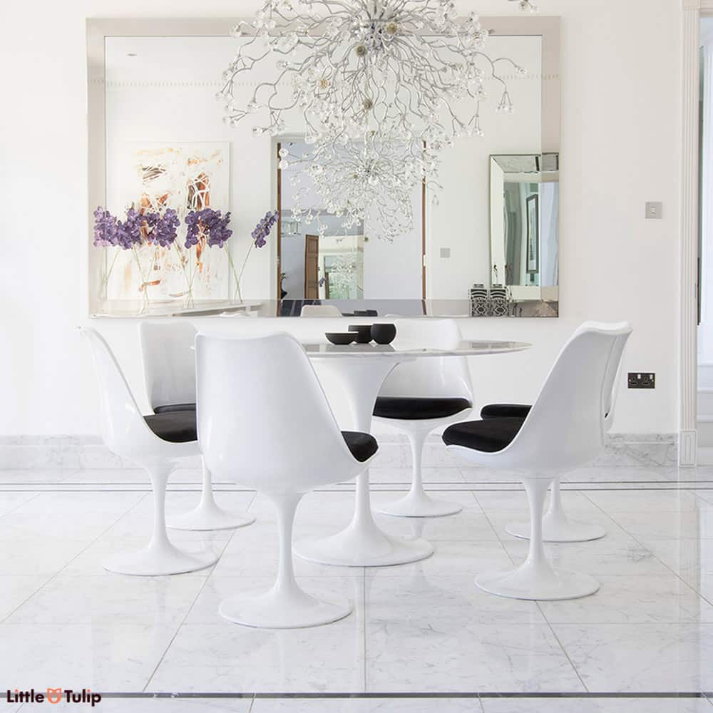 A truly classic set, the largest 120 cm circular Carrara Marble Tulip Table flanked by six wonderful matching Tulip Side chairs with black cushions
