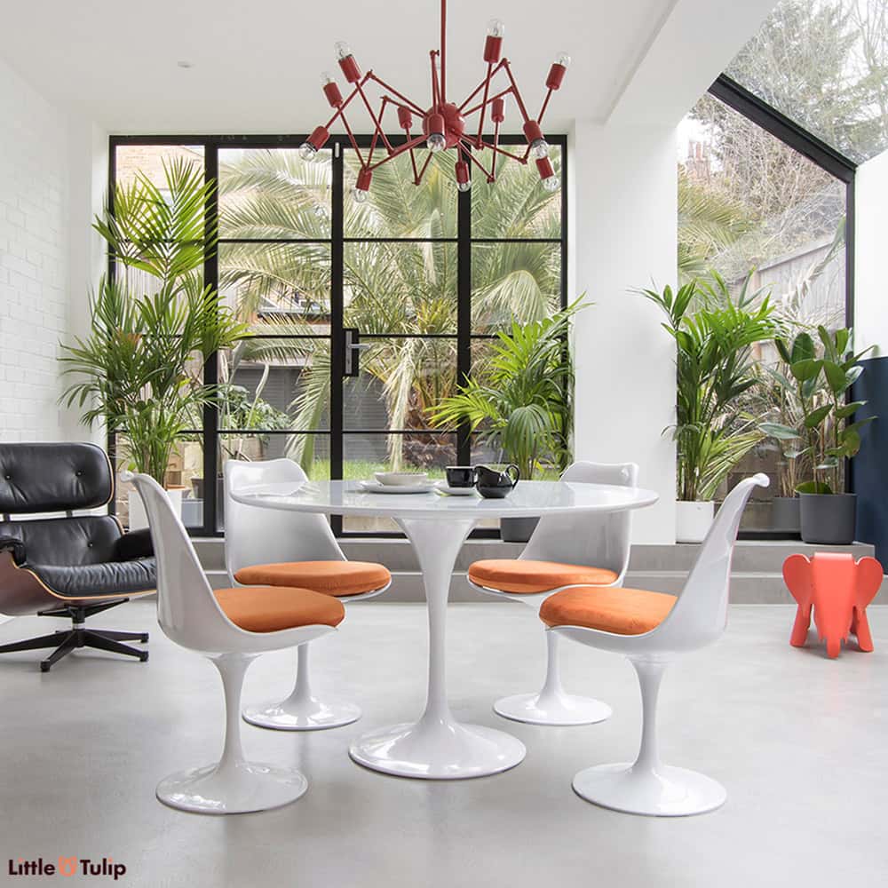 The beautiful sheer white sheen of the original classic 120 cm Tulip Table is perfect with a group of 4 Tulip Side Chairs with soft velvety orange cushions
