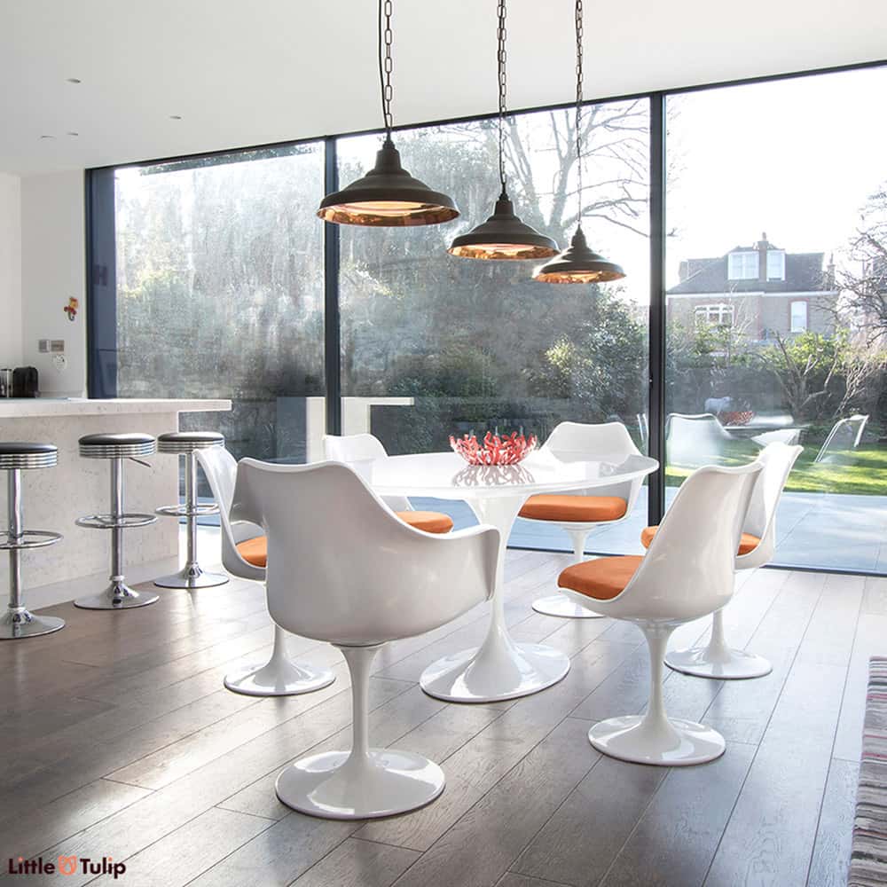 Under the lights, the classic white 170 cm oval Saarinen Tulip table is flanked by 4 Tulip Sides and 2 Tulip Arm chairs & finished with orange cushions