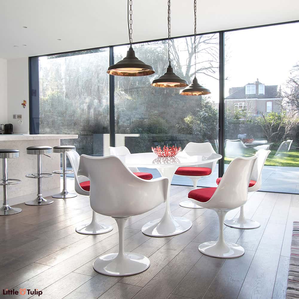Under the lights, the classic white 170 cm oval Saarinen Tulip table is flanked by 4 Tulip Sides and 2 Tulip Arm chairs & finished with red cushions
