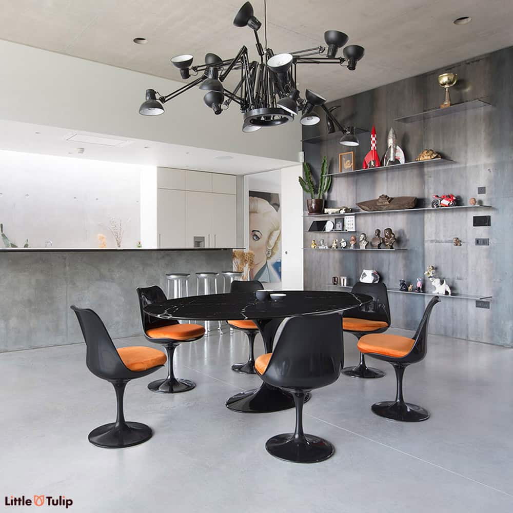 The ultimate alternative dining room style featuring the black Nero Marquina Tulip Oval table & 6 black Tulip side chairs splashed with orange cushions 