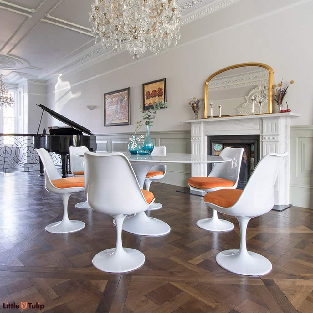 A majestic dining room, complete with piano, brought to life by a Saarinen Tulip 200 cm oval dining table & six chairs, finished in soft orange seat pads