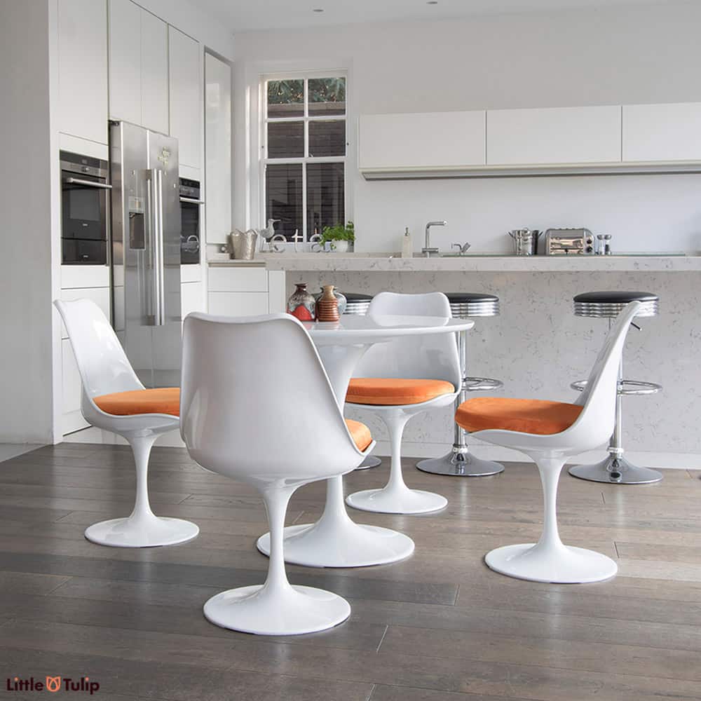 A super clean cut look is achieved in this light spacy kitchen by the 90cm classic White Tulip Table & four matching side chairs with bright orange cushions