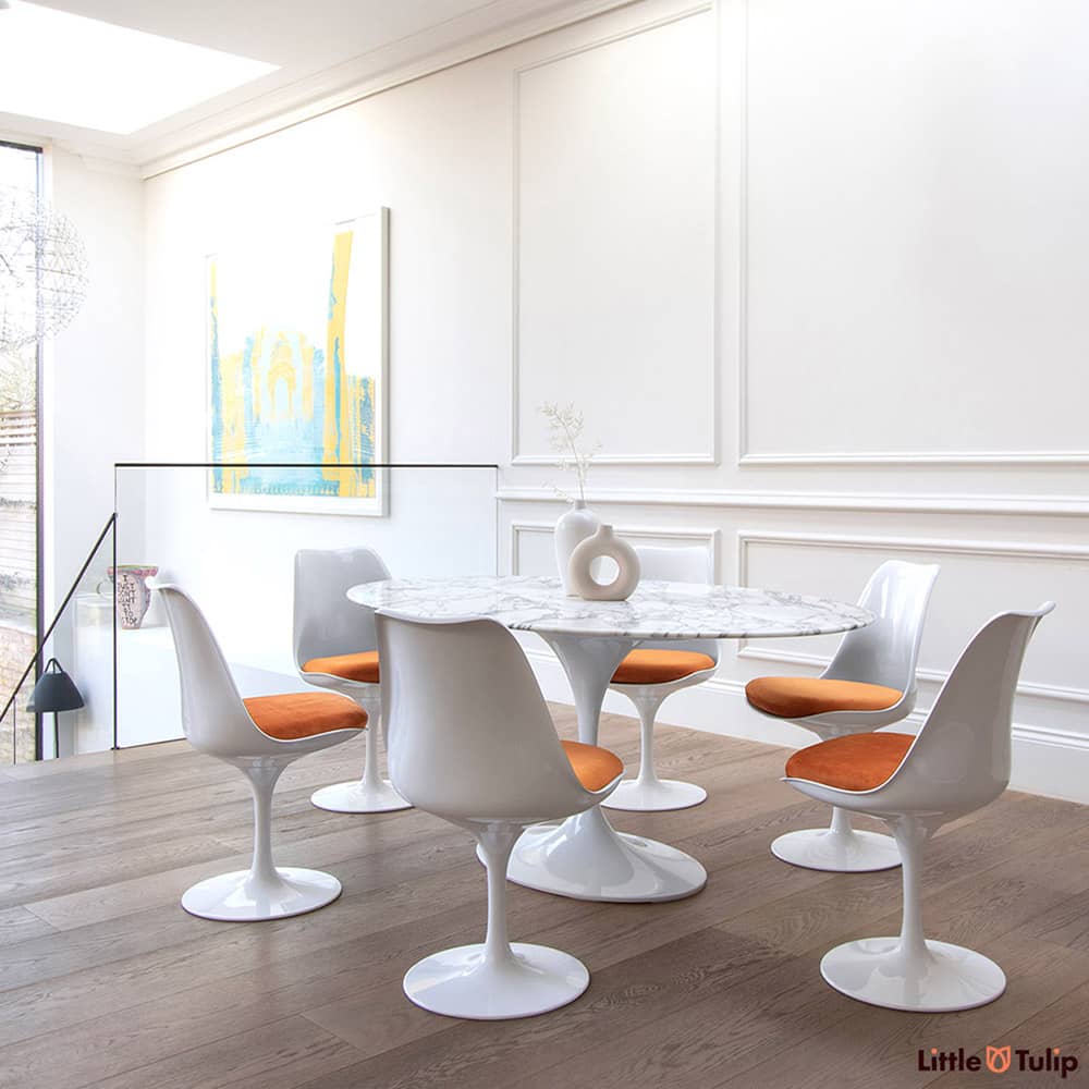 A medium sized Oval 170 x 110 cm Tulip table and 6 matching tulip chairs with orange cushions look amazing with Arabescato marble in this modern home